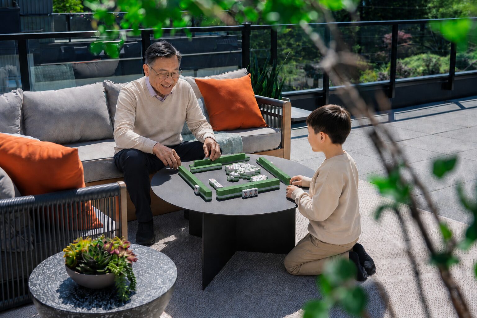 Grandfather and grandson playing mahjong on the private rooftop patio of an Addition townhome in Langley