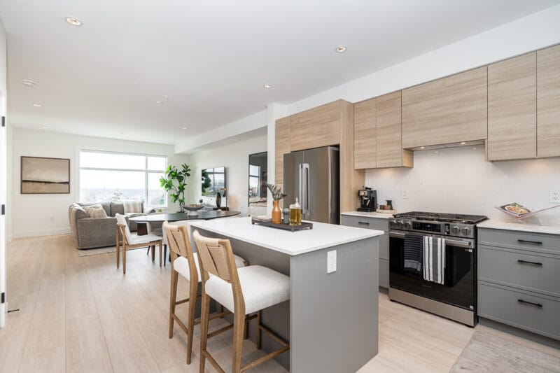 Open kitchen with island seating and the living area in the Addition Plan D show home